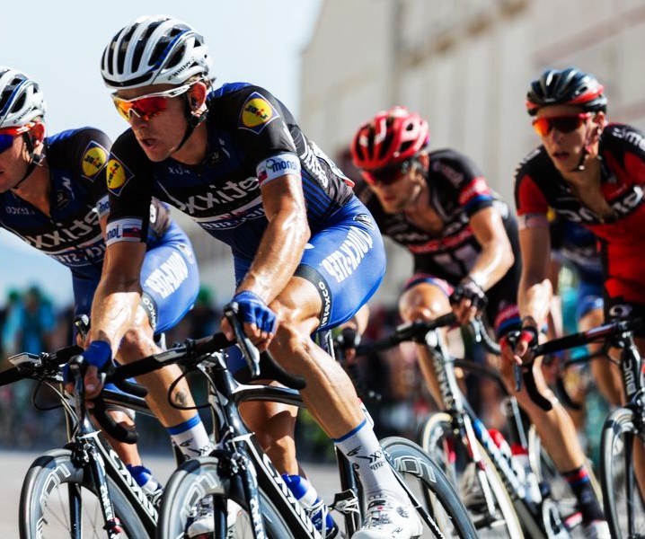 Group of road cyclists riding together in a tight formation during a race on a sunny day
